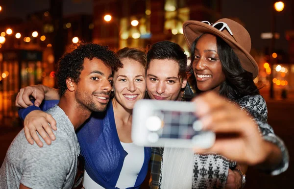 Grupo multiétnico milenario de amigos tomando una foto selfie con teléfono móvil en la terraza de la azotea usando flash por la noche — Foto de Stock