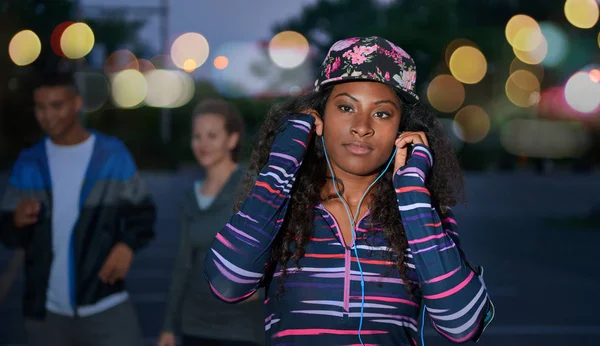 アフリカ系アメリカ人千年の選択の少女彼女のスマート フォンで音楽屋外都市公園で彼女の友人と夜遅く. — ストック写真