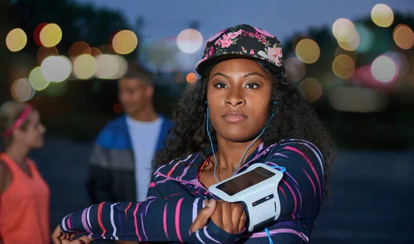 Afro-Amerikan bin yıllık kız streching omuzları açık havada bir parkta kentsel geç akşam arkadaşları ile. — Stok fotoğraf