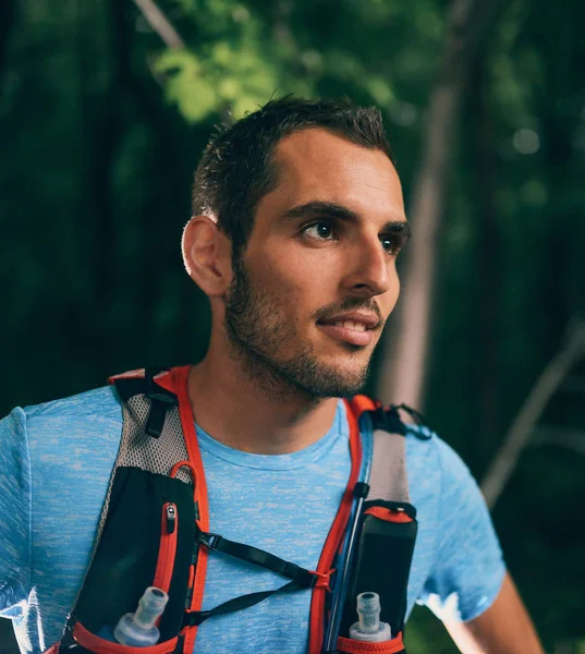 Ajuste jogger masculino descansando durante el entrenamiento diurno para la carrera de senderos forestales a campo traviesa en un parque natural . — Foto de Stock