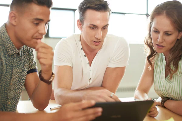 Grupo de emprendedores creativos en una oficina de concepto abierto reunidos en una tableta digital . — Foto de Stock