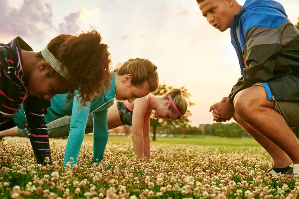 Diverse group of women during a fitness training doing push-ups at sunset in nature park — Stock Photo, Image