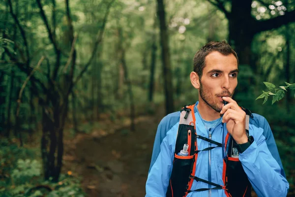 Ajuste jogger masculino hidrata mientras que el entrenamiento del día para la carrera de senderos forestales a campo traviesa en un parque natural . — Foto de Stock