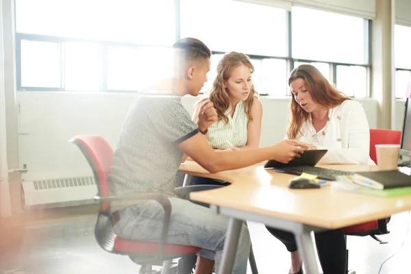 Grupo não representado de empresários criativos em um escritório de conceito aberto que faz brainstorming juntos em um tablet digital . — Fotografia de Stock