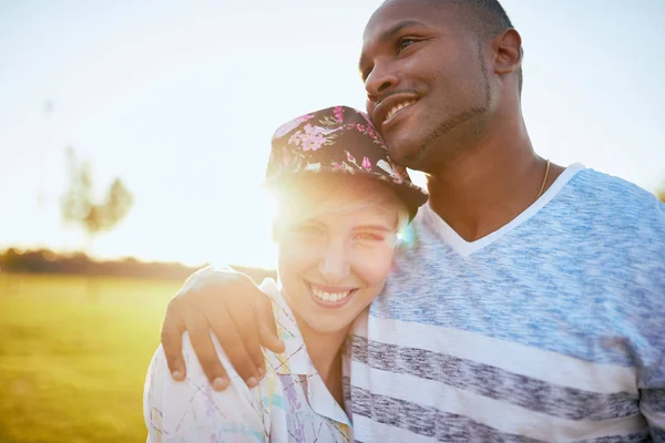 Pareja mixta de millennials en un campo de hierba abrazándose y mostrando afecto juntos — Foto de Stock