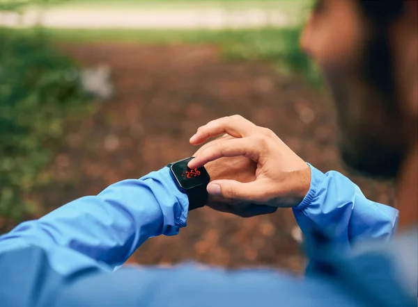 Sprawny mężczyzna jogger dzień za pomocą zegarka smartwatch podczas Krzyż kraju lasu szlak wyścigu w parku przyrody. — Zdjęcie stockowe