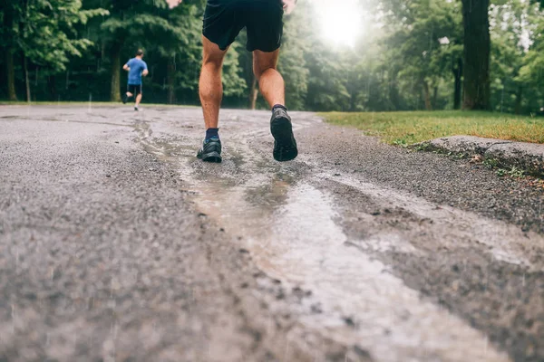 Muskulös kalvar av fit manliga jogger utbildning för gränsöverskridande land forest trail race i regnet på en naturstig. — Stockfoto