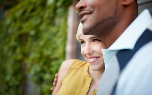 Atractiva y elegante pareja multicultural enamorada abrazada por una valla en un entorno urbano lleno de hiedra — Foto de Stock