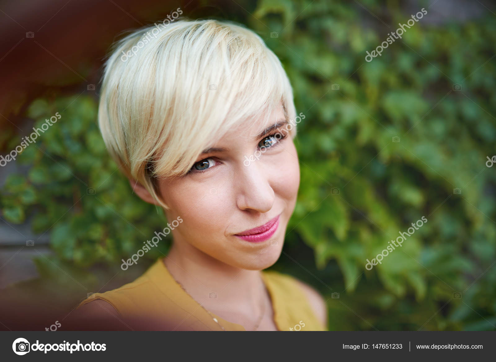 Attractive White Woman Taking A Selfie Against An Ivy Fence