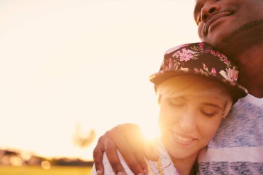 Millennials sarılma ve birlikte bir sevgi gösterisi bir çim alan içinde karışık yarış çift