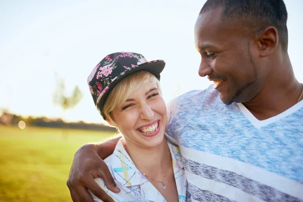 Pareja mixta de millennials en un campo de hierba abrazándose y mostrando afecto juntos — Foto de Stock