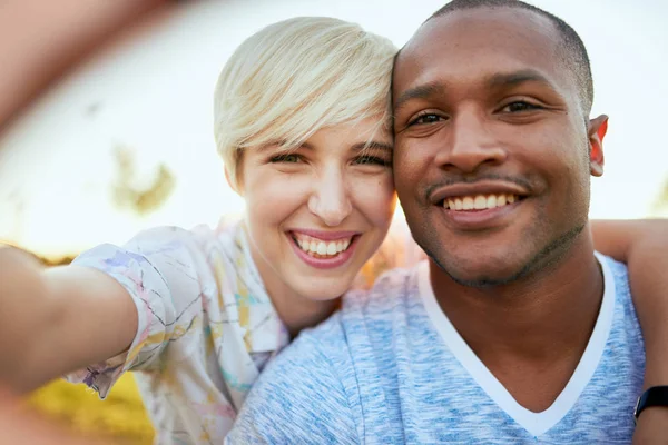 Pareja de carreras mixtas de millennial en un campo de hierba tomando una selfie con un smartphone — Foto de Stock