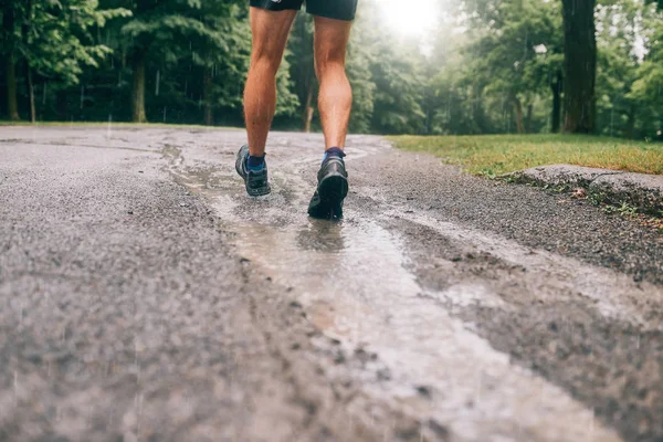 Gespierde kalveren van fit mannelijke jogger training voor grensoverschrijdende land bos trail wedstrijd in de regen op een natuurpad. — Stockfoto