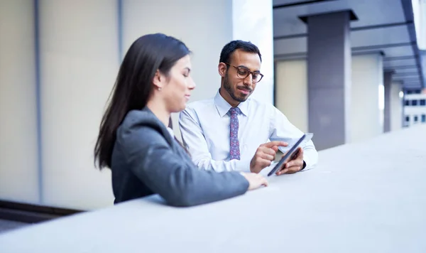 Mixed race couple of co-workers reviewing social media strategy with a tablet