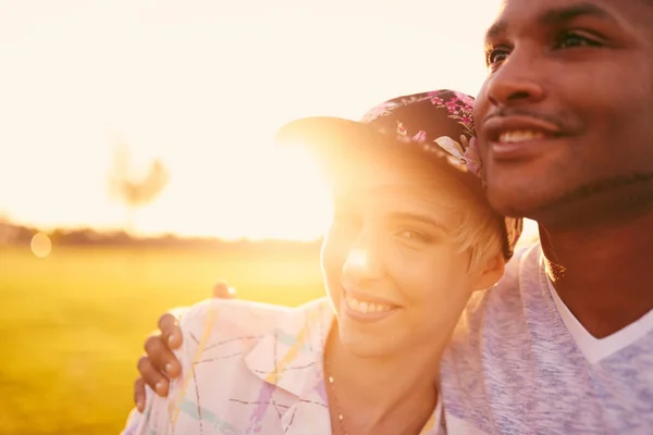 Mixed race couple of millennials in a grass field cuddling and showing affection together — Stock Photo, Image