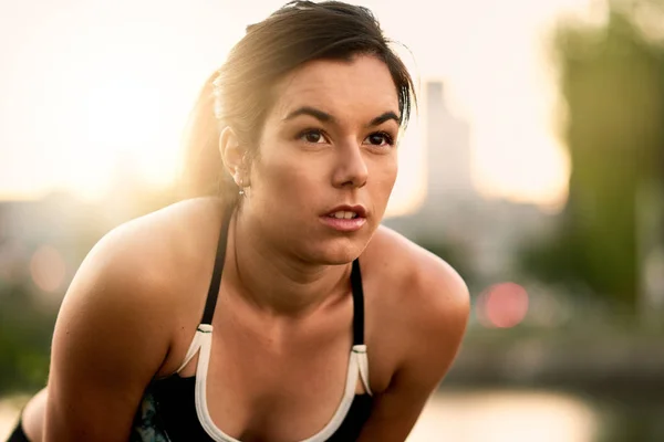 Portret kobiety aktywne millenial joggingu o zmierzchu z miejski gród i zachód słońca w tle — Zdjęcie stockowe