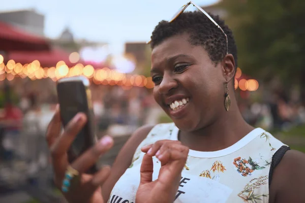 Authentic young african american woman using a mobile phone at a summer music festival — Stock Photo, Image