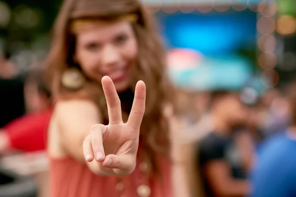 Attraente ragazza ispanica che fa un gesto di pace tra la folla di un festival musicale estivo — Foto Stock