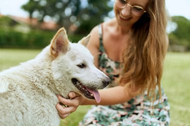 Genç, güzel sarışın kız dışarıda, dost canlısı köpek yavrusuyla oynuyor.