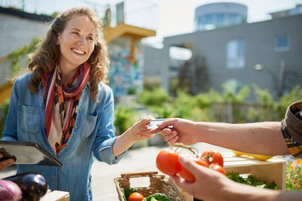 Mujer amigable cuidando un puesto de verduras orgánicas en un granjero —  Fotos de Stock