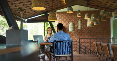 Elinde kahve fincanı tutan genç bir kadın Duri 'ye gülümsüyor.