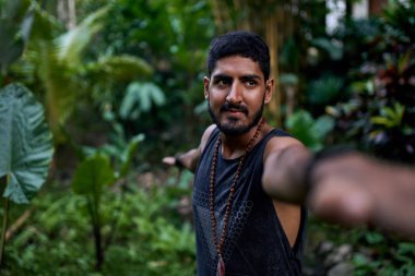 Genç sağlıklı çekici erkek tropikal bölgede asana yogası yapıyor.