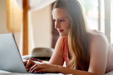 Yatakta uzanan güzel bir kadın dizüstü bilgisayarla sohbet ederken...