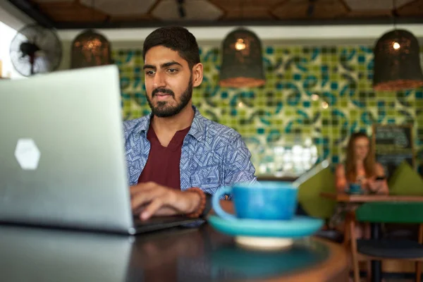 Handsome millennial indian man working in trendy coworking space