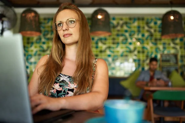 Attraente donna millenaria che distoglie lo sguardo pensando mentre lavora — Foto Stock