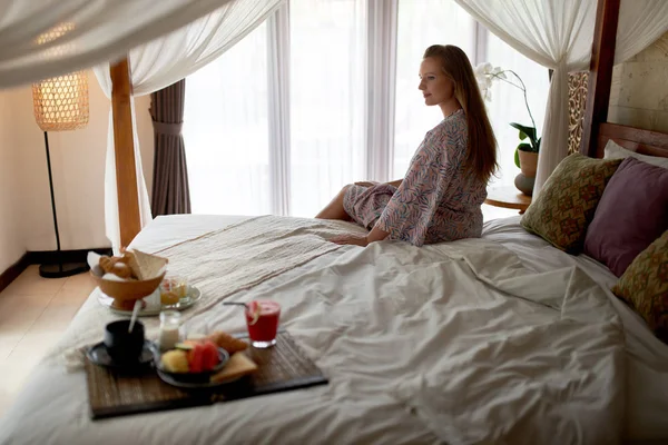 Спокійна красива жінка з халатом, що сидить у світлій кімнаті готелю — стокове фото