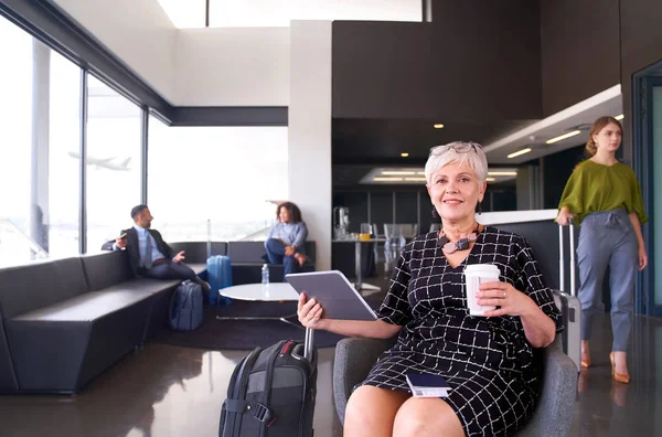 Professionell kvinna sitter på flygplatsen bär trendig klänning smili Stockbild