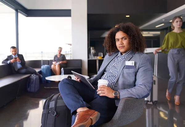 Uomo afroamericano in attesa di volo seduto in moderno aeroporto Immagine Stock