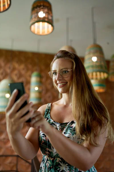 Hermosa mujer milenaria con gafas usando smartphone para vid Fotos De Stock