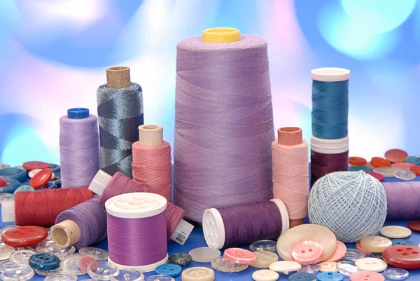 Spools of thread and buttons  are on artistic many-colored background — Stock Photo, Image