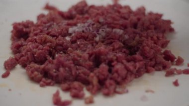 Yavaş çekimde etli tartar pişirin. Taze soğan dilimleri doğranmış etin üzerine dökülüyor ve çatallarla karıştırılıyor.. 