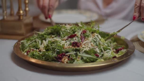 Frauenhände, die in Zeitlupe frischen Salat mit sonnengetrockneten Tomaten, Pinienkernen und Parmesan auf den Teller bringen. — Stockvideo
