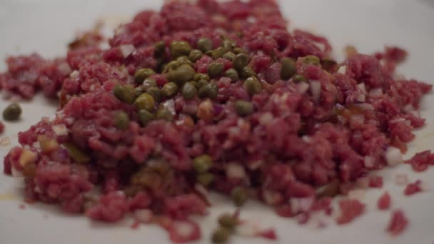 Närbild av matlagning kött tartar i slow motion. Kapris som blandas med hackat kött med gafflar. — Stockvideo