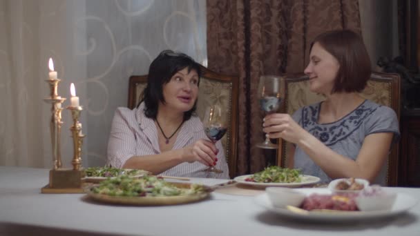 Brunette femmes adultes avec sa fille dîner avec du vin au ralenti. Amis féminins parler et manger dans l'intérieur classique avec des bougies . — Video