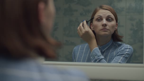 Jonge vrouwelijke volwassene aanbrengen make-up in spiegel reflectie in slow motion. Vrouw aanbrengen mascara voor wimpers en glimlachen. — Stockvideo