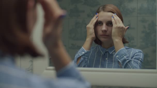 Молодая женщина в рубашке наносит макияж в зеркальном отражении в замедленной съемке. Женщины кладут увлажняющий крем с руками на лицо . — стоковое видео
