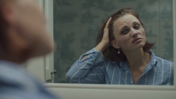 30-jährige erwachsene Frau im Hemd, die in Zeitlupe in den Spiegel schaut. Alkoholisierte Frau hat Kopfschmerzen. — Stockvideo