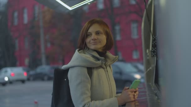 Jeune femme brune avec sac à dos achetant une boisson chaude au camion de nourriture de rue. Femme qui a froid en attendant le thé dans la rue . — Video