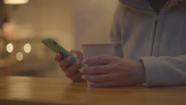 카페에서 커피와 스마트폰을 들고 있는 여성 손을 꽉 잡고 있는 창문은 천천히 움직이고 있다.. — 비디오