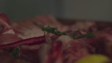 Limonlu çiğ et dilimleri ve beyaz eldivenli elleri olan biberiyeli taze biftek. Kapat. 