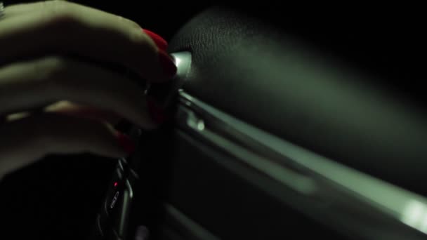 Close up of female hand with red nails turning on volume in car radio. — Stock Video