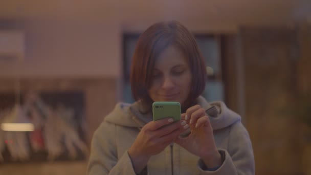 Jonge vrouwen in jas nemen foto van een kopje koffie in cafe, venster geschoten in slow motion. — Stockvideo