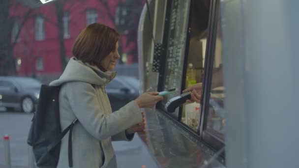 Γυναίκα με σακίδιο πληρώνουν με smartphone για καφέ στο δρόμο φορτηγό τροφίμων. Σύστημα ανέπαφων τραπεζικών πληρωμών. — Αρχείο Βίντεο