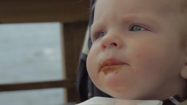 Retrato de comer menino recém-nascido com o mar no fundo. Lábios recém-nascidos sujos . — Vídeo de Stock
