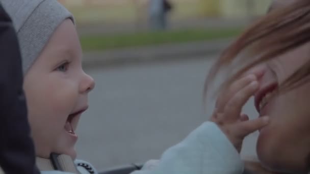 Nyfödd pojke rör vid sin mammas näsa och ler. Mor skakar på huvudet och skrattar. — Stockvideo