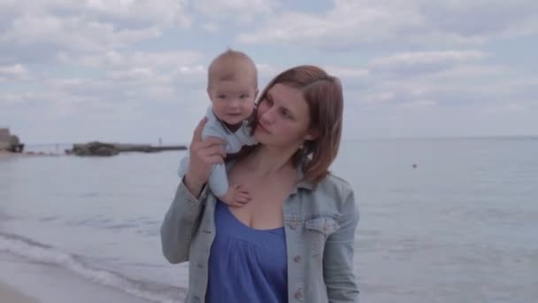 Matka drží svého novorozence na rameni u moře. — Stock video